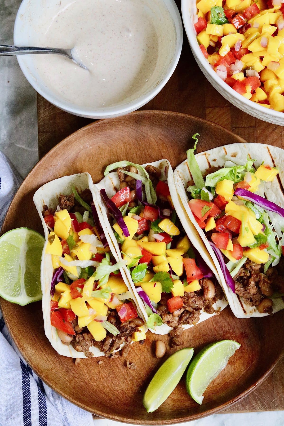 mango tomato salsa and jerk sauce in bowls beside taco shells filled with meat filling