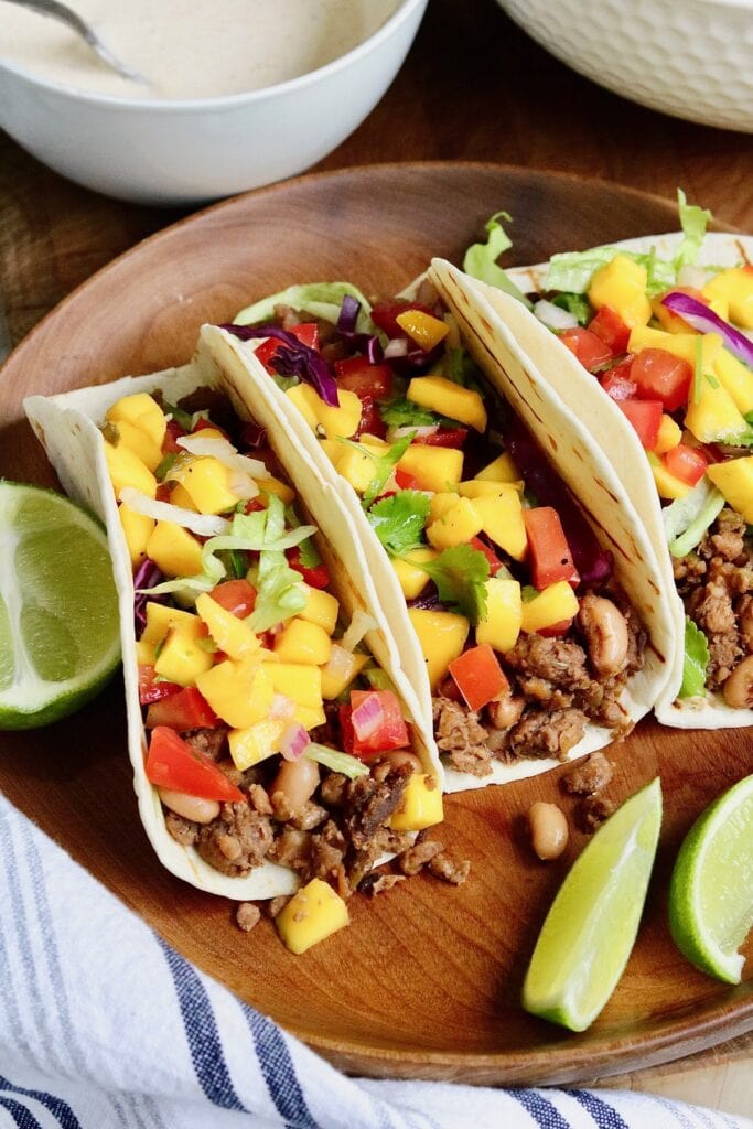 three vegan tacos on a plate with salsa and jerk sauce