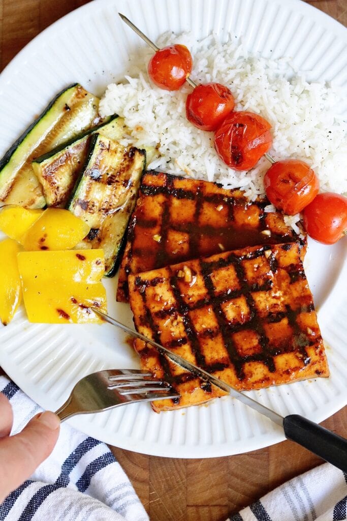 grilled bbq tofu on a plate with veggie skewers and rice