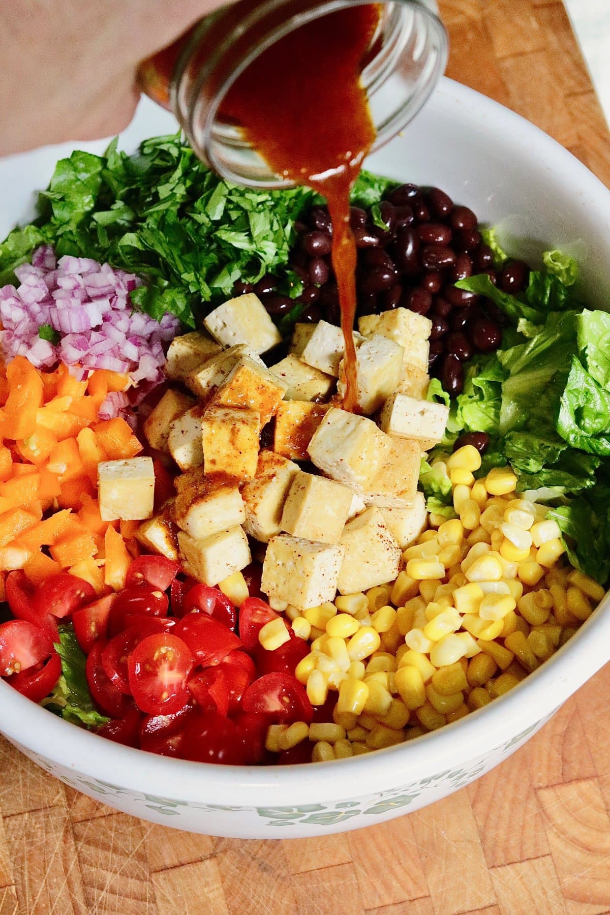 chipotle lime dressing being poured over Mexican chopped salad in a bowl