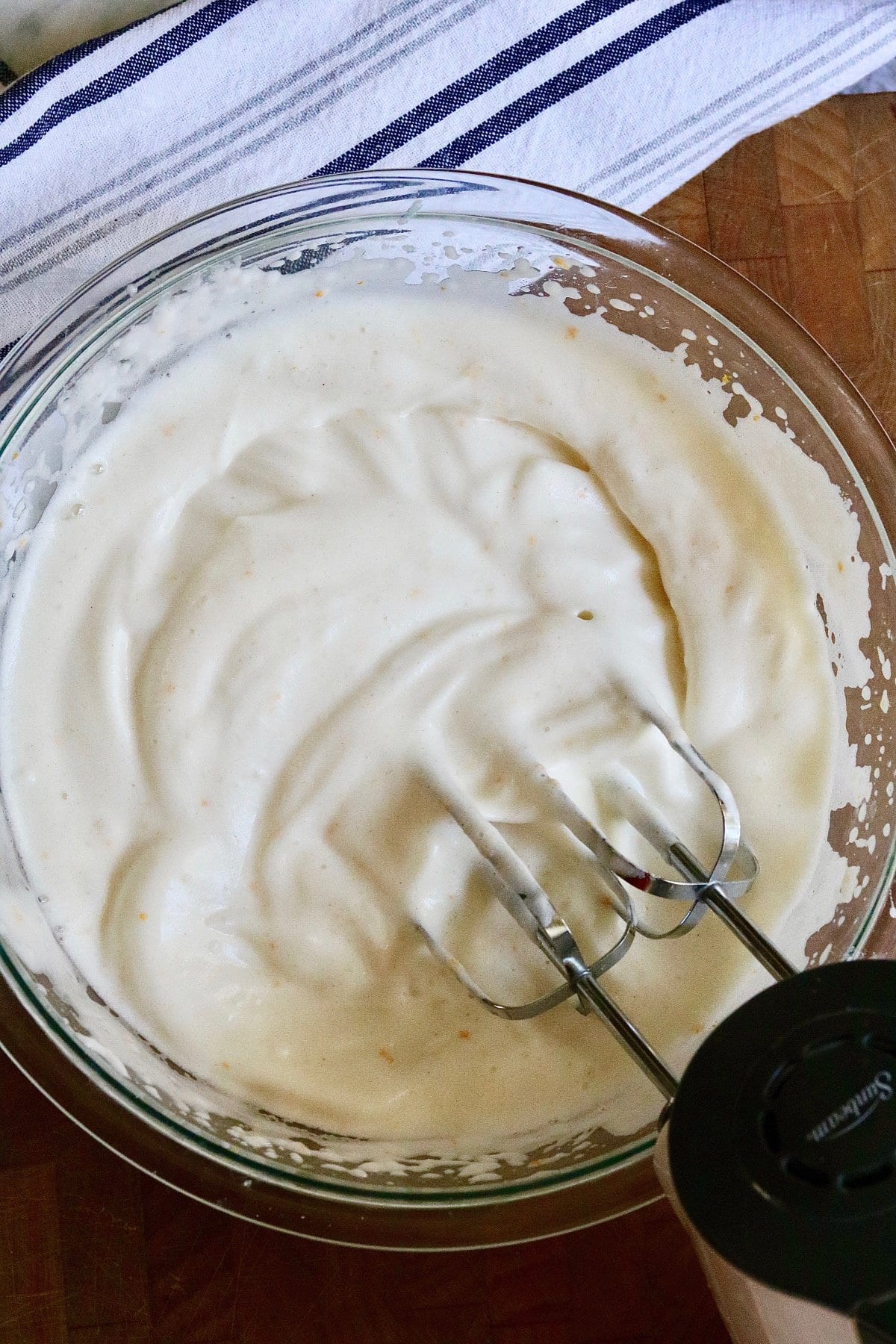 aquafaba in a bowl being whipped into cream with electric hand mixer