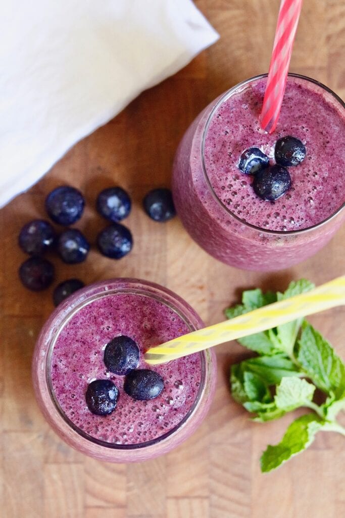 overhead shot of blueberry banana smoothies in glasses with straws