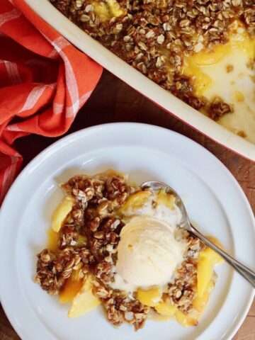 vegan peach crisp on a plate with a scoop of vanilla ice cream