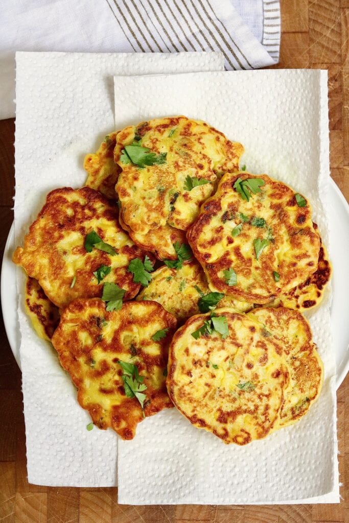 vegan corn fritters on a paper towel lined plate 