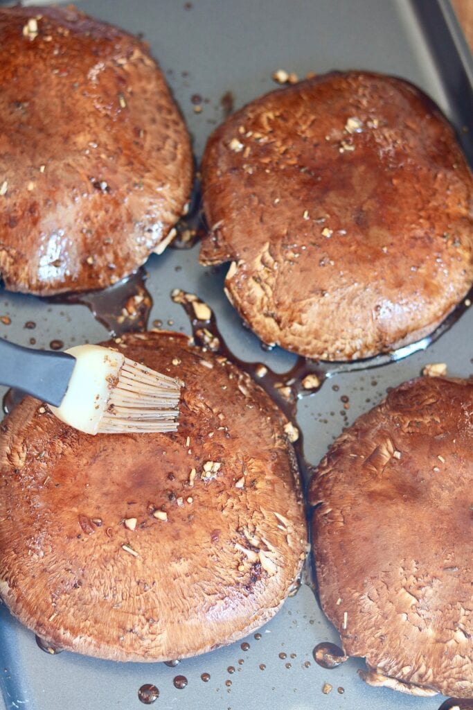 portobello mushroom caps being brushed with marinade ingredients 