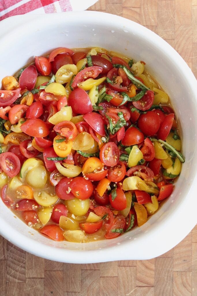 cherry tomatoes marinating in a bowl for spaghetti pasta dish