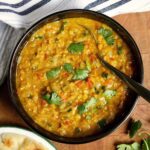 red lentil dahl in a bowl beside a plate of vegan naan