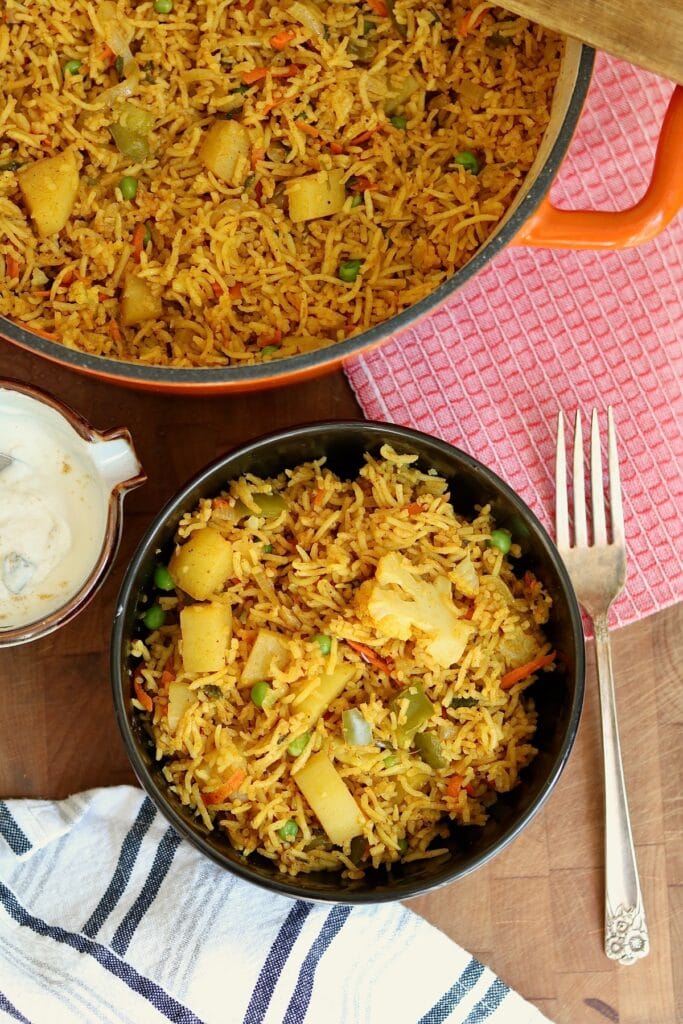 a bowl of vegetable biryani with a fork