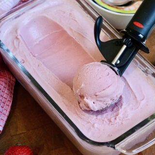 vegan strawberry ice cream being scooped out of container