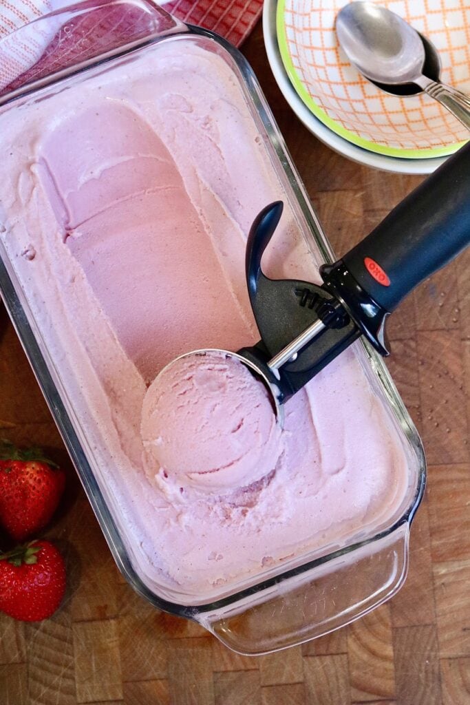 vegan strawberry ice cream being scooped into a bowl