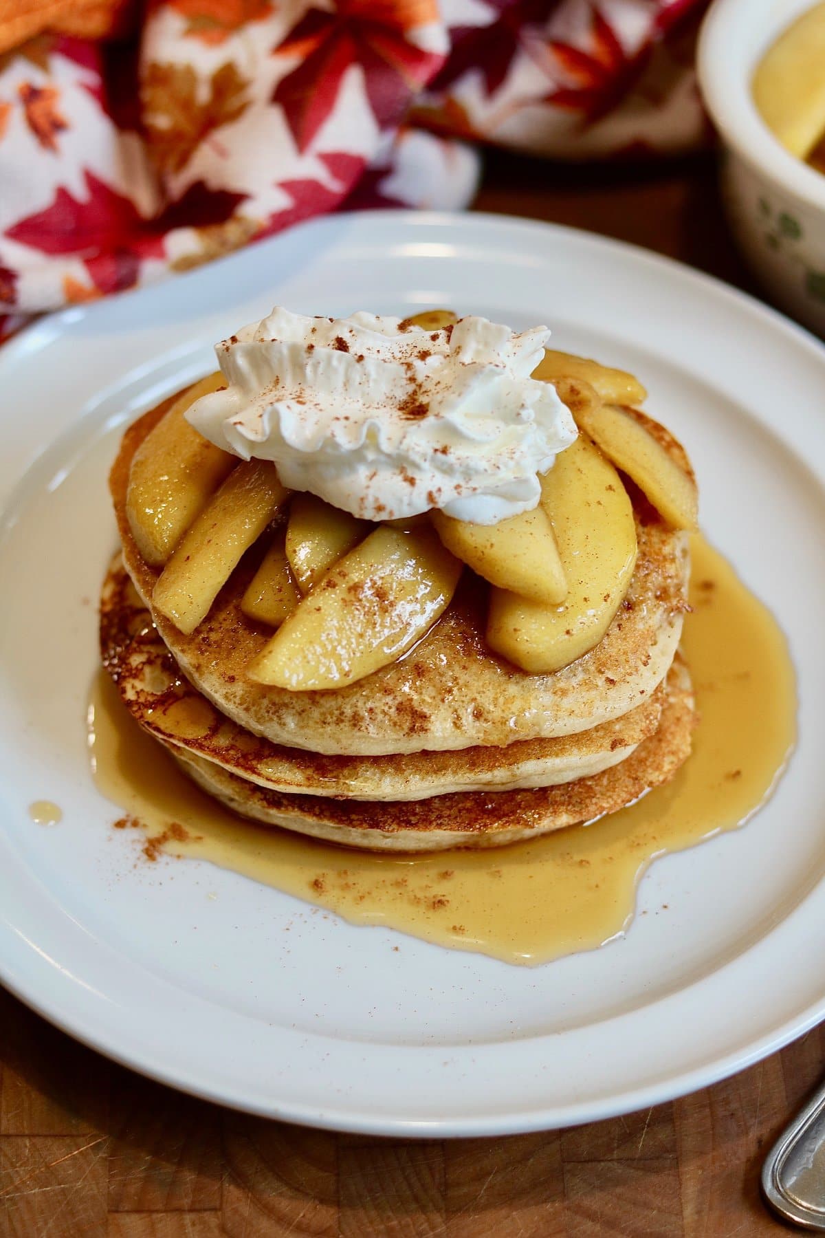 a stack of vegan apple cinnamon pancakes topped with apple compote and whipped cream