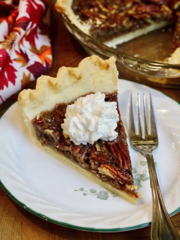a slice of vegan pecan pie on a plate with whipped cream