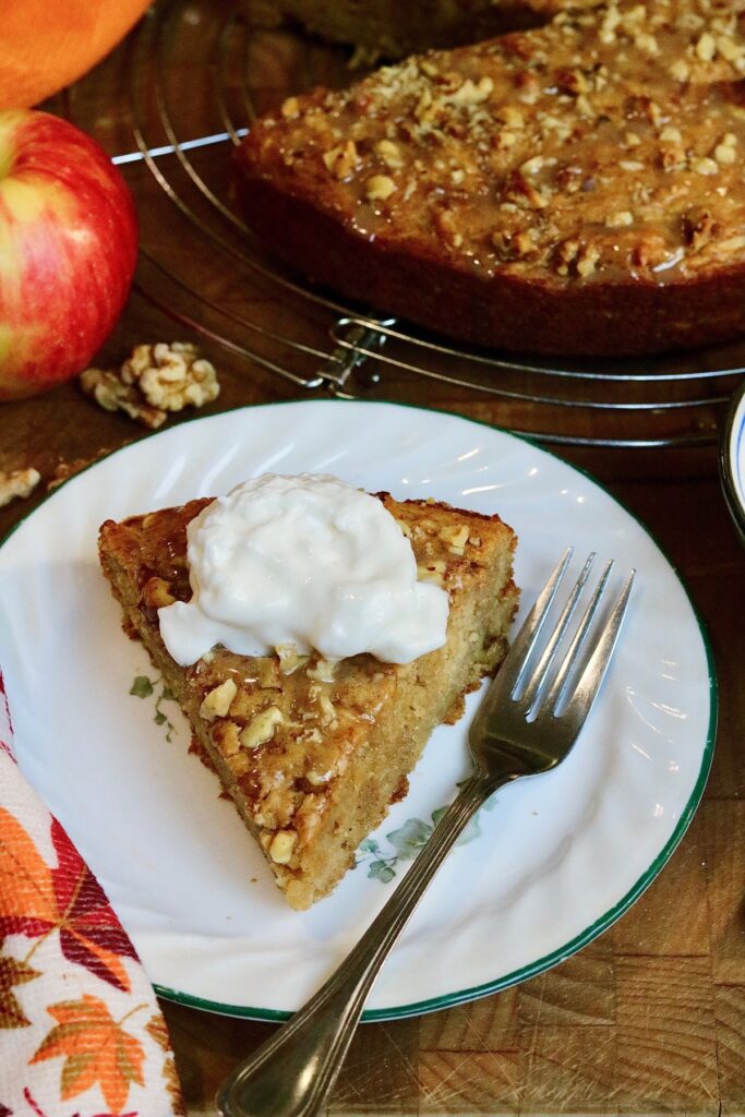 a slice of vegan apple cake topped with whipped cream