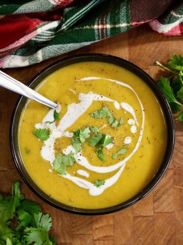 a bowl of vegan curried butternut squash soup with a spoon