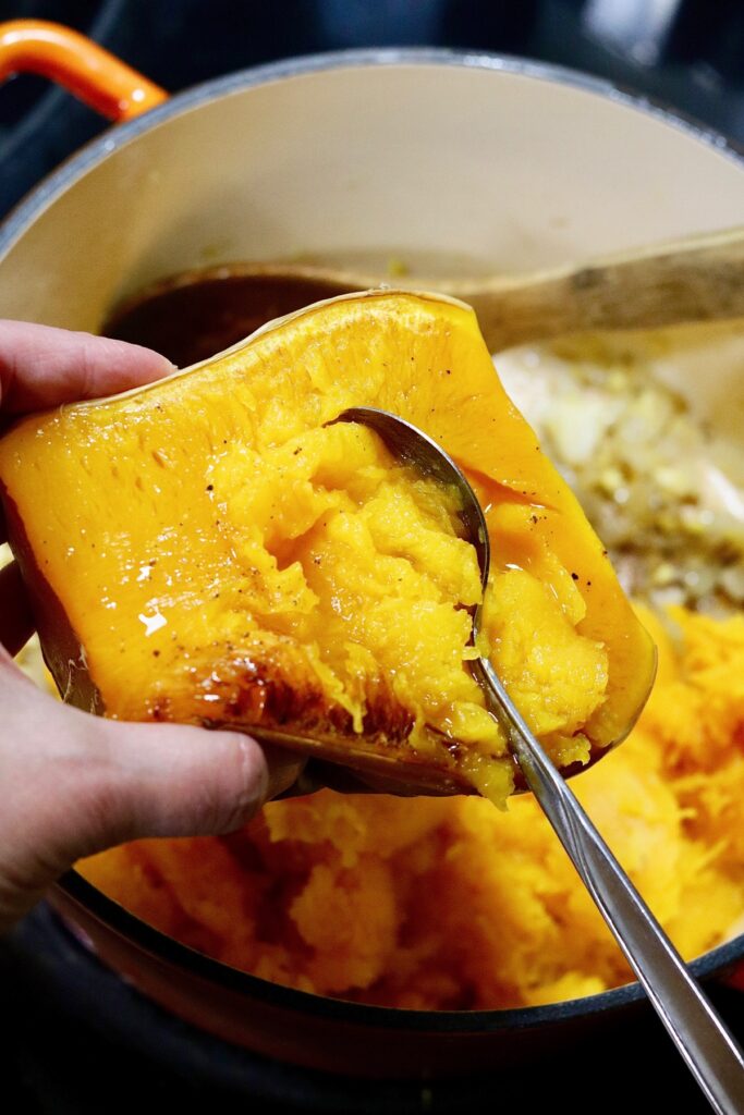 roasted butternut squash being scooped into a soup pot