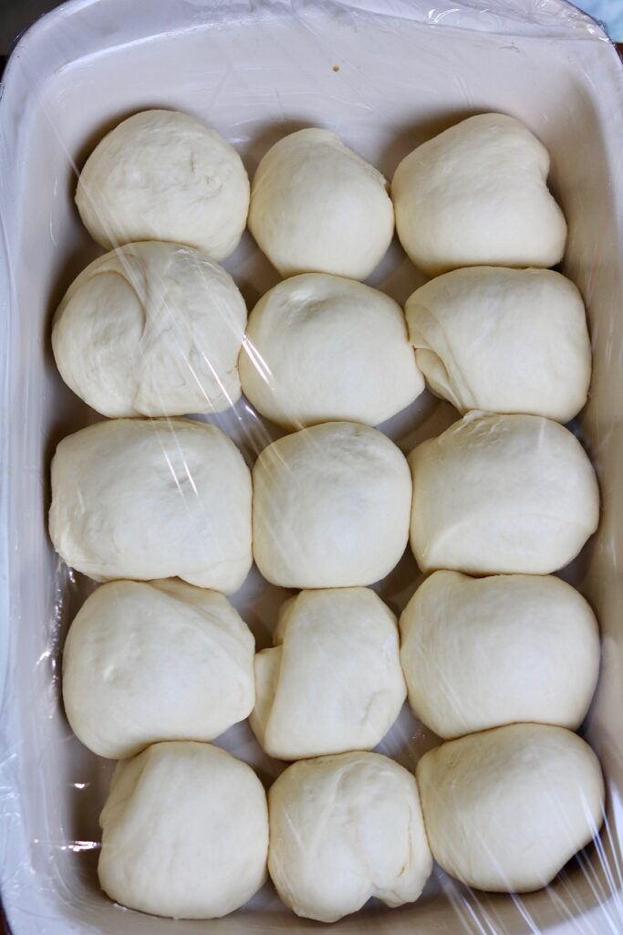 vegan dinner rolls dough balls rising in a baking dish