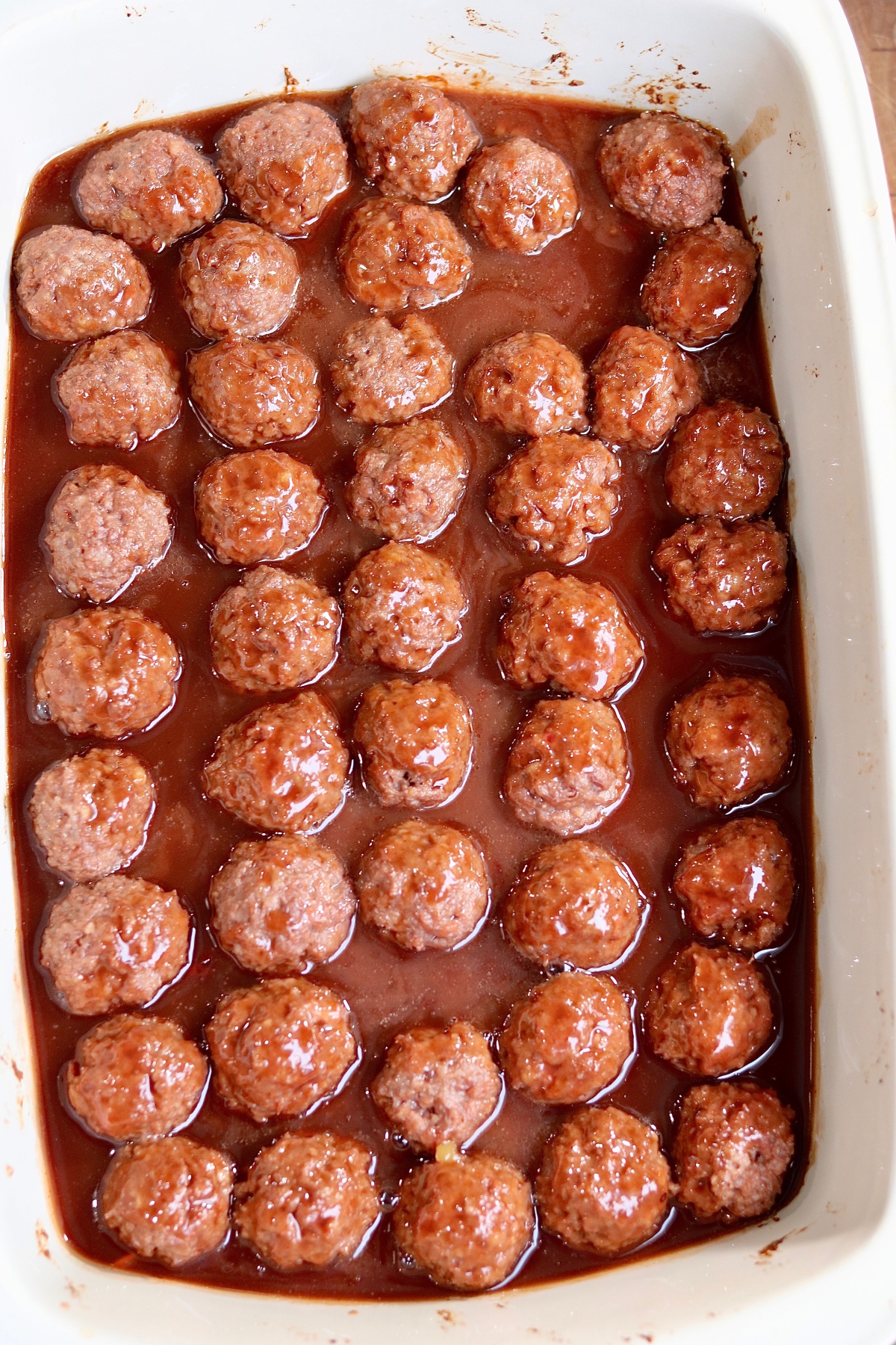 vegan meatballs in casserole dish with grape jelly bbq sauce ready to bake