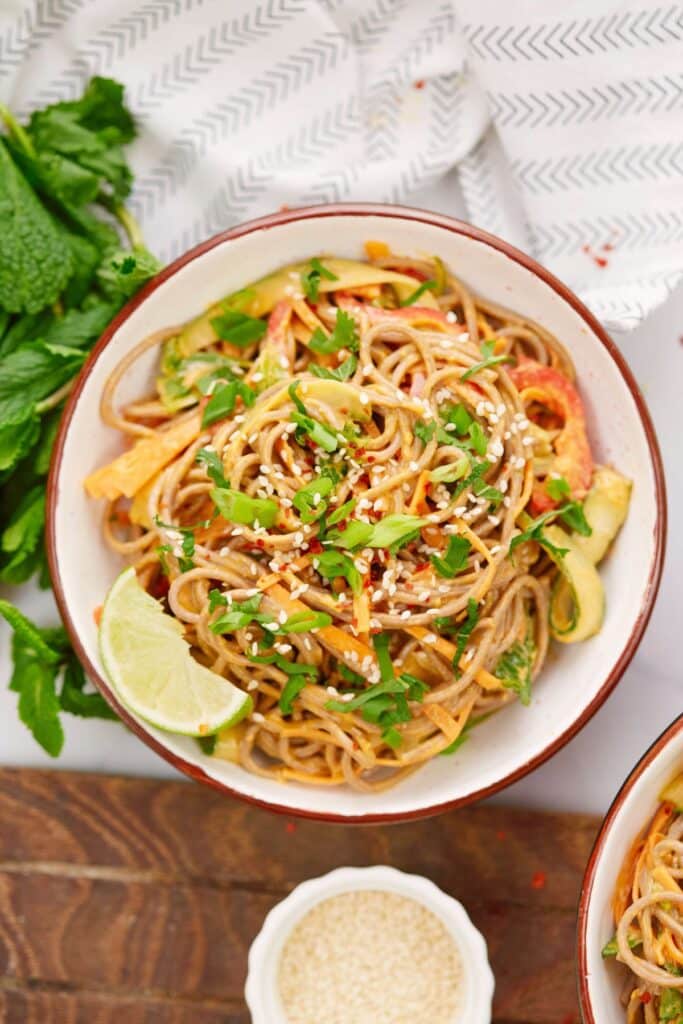 cold soba noodle salad in bowl topped with fresh cilantro and lime wedges