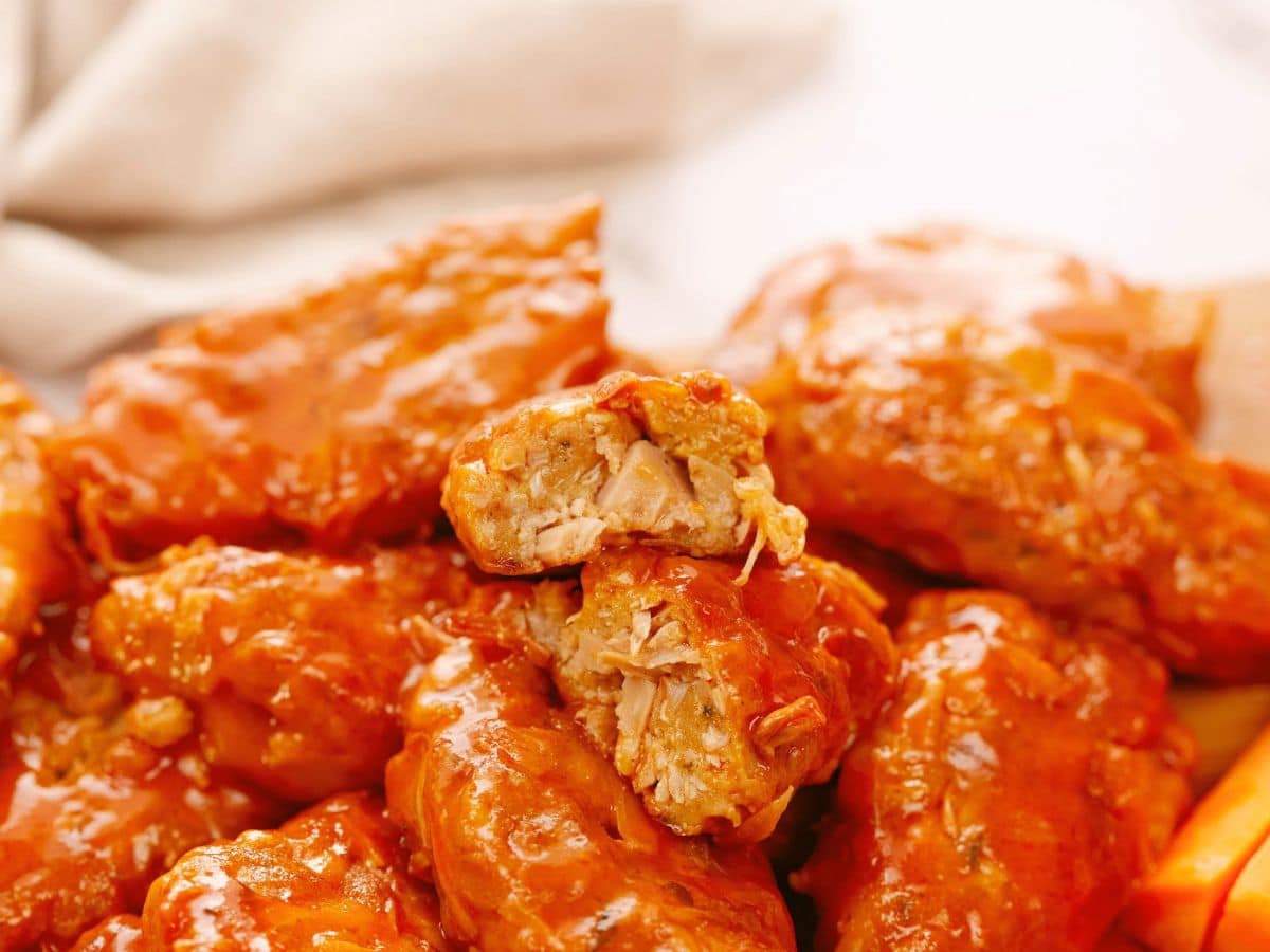 jackfruit vegan wing cut in half on top of stack of vegan buffalo wings