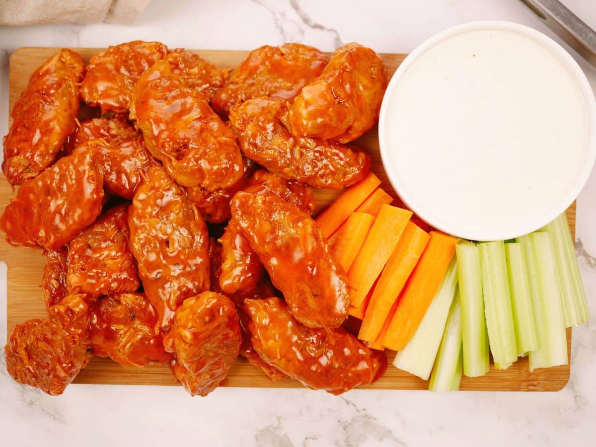 wood platter of jackfruit buffalo wings by bowl of dpping sauce on table