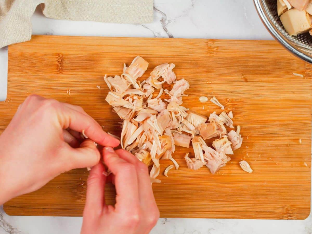 hands shredding jackfruit on cutting board