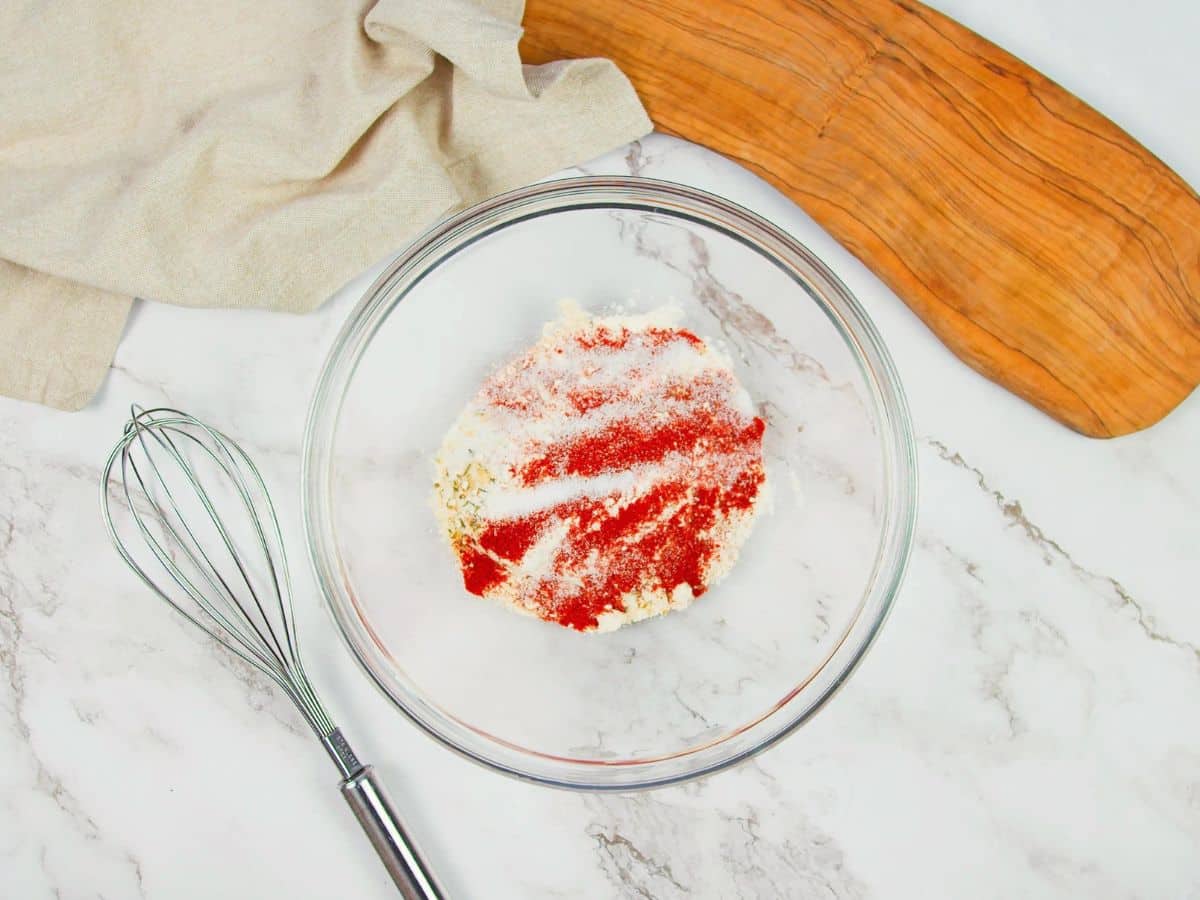 spices and flour in glass bowl on marble counter beside whisk