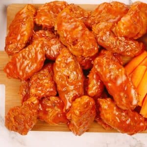 stack of jackfruit vegan wings coated in sauce on wood cutting board