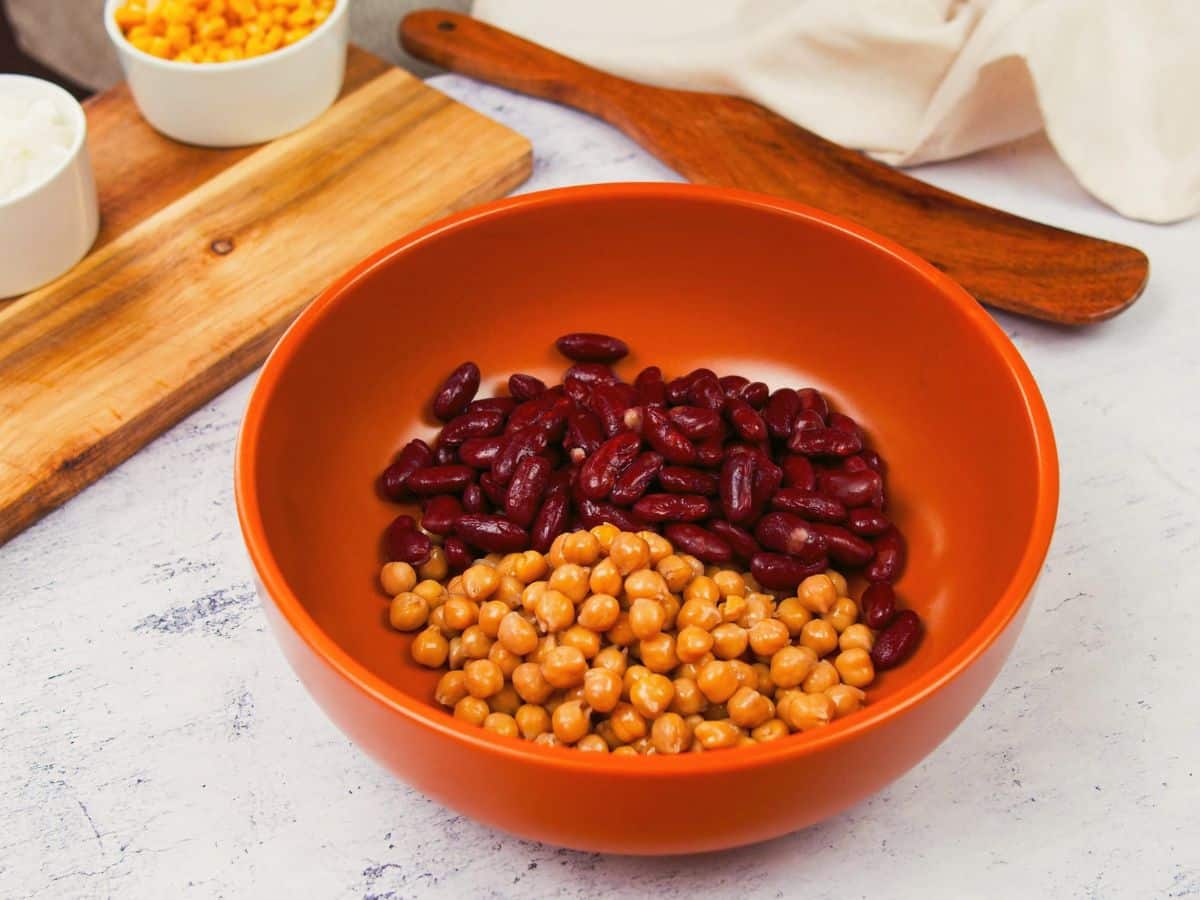 burnt orange bowl with kidney beans and chickpeas sitting on marble counter