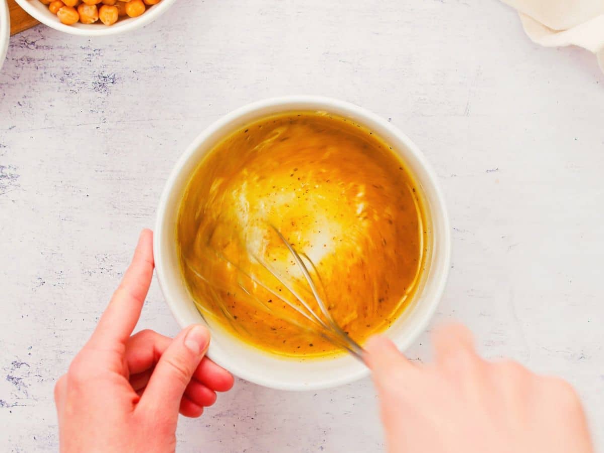 hand whisking dressing in white bowl