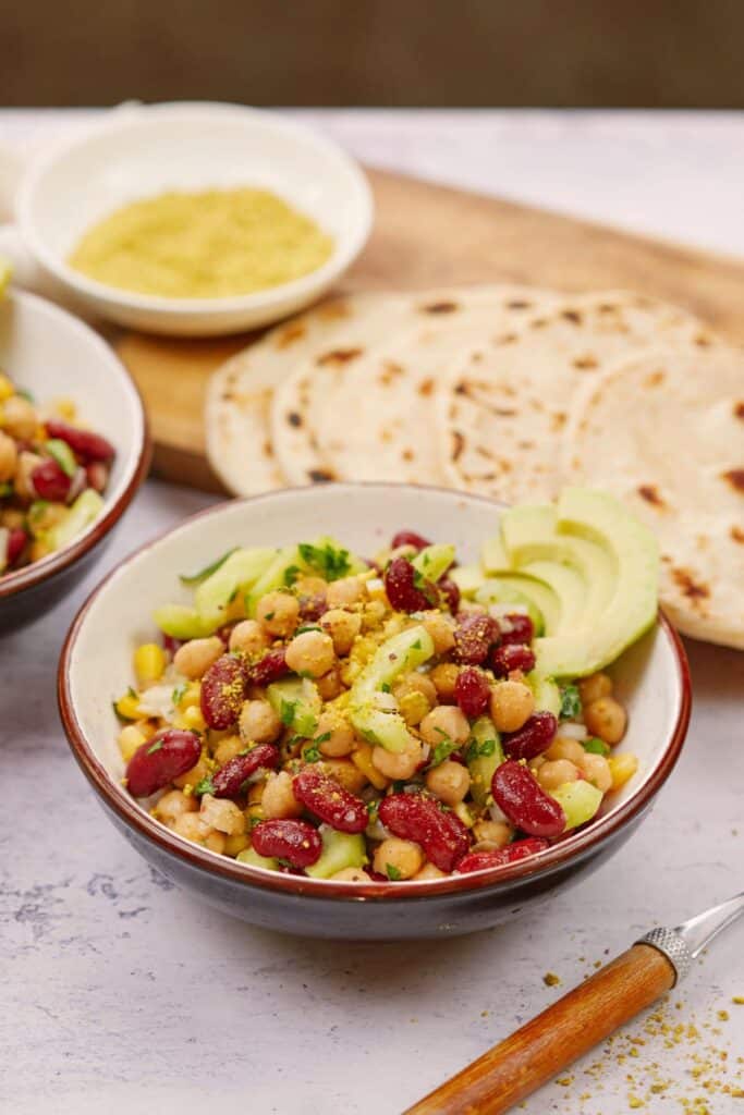 kidney bean salad in bowl by wood cutting board of tortillas and sauce