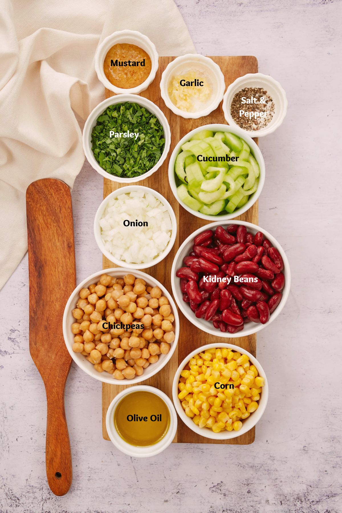 variety of white ramekins on cutting board filled with ingredients for bean salasd