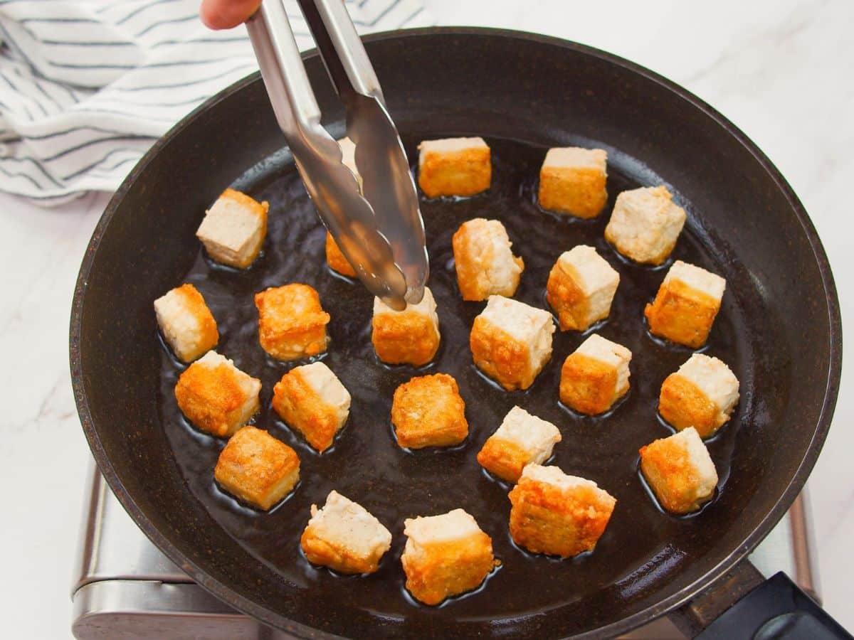 tofu cubes being fried in skillet