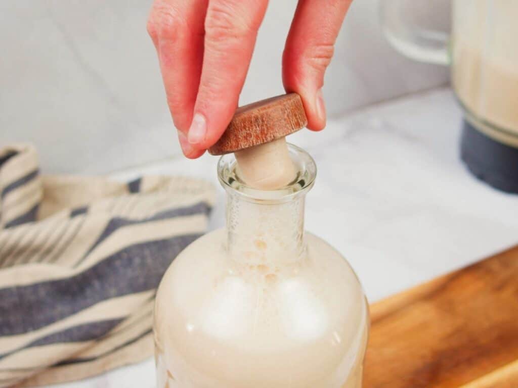hand putting cork into jar