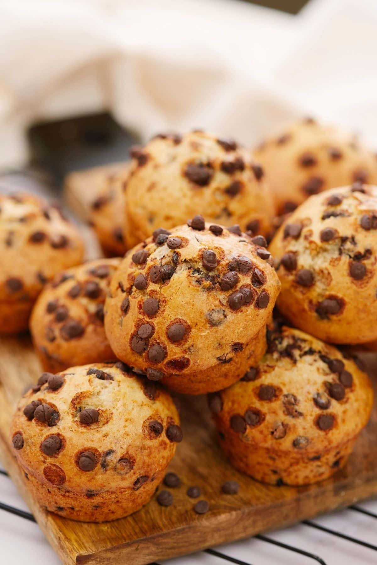 vegan muffins stacked on top of wood board on wire rack