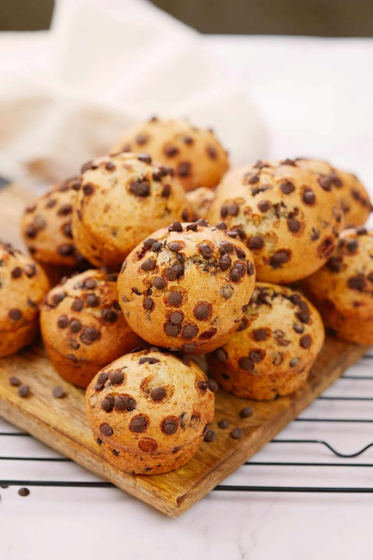 wood cutting board of vegan chocolate chip muffins on top of wire rack