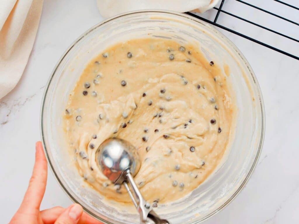 glass bowl of muffin batter with scoop in the side