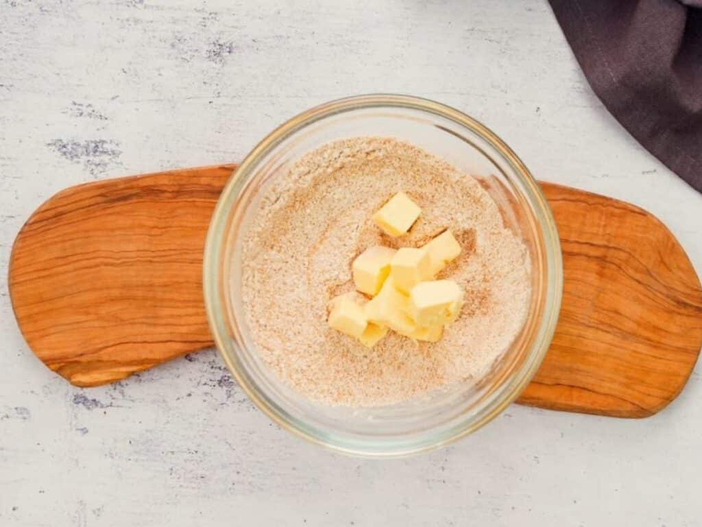 butter, sugar, and flour in glass bowl sitting on wooden board