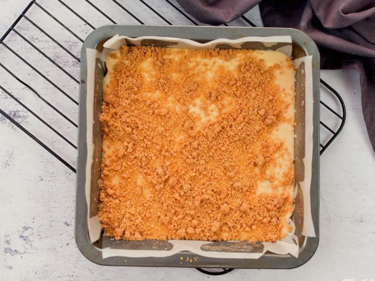 square baking dish with coffee cake batter and crumb topping on top of wire rack