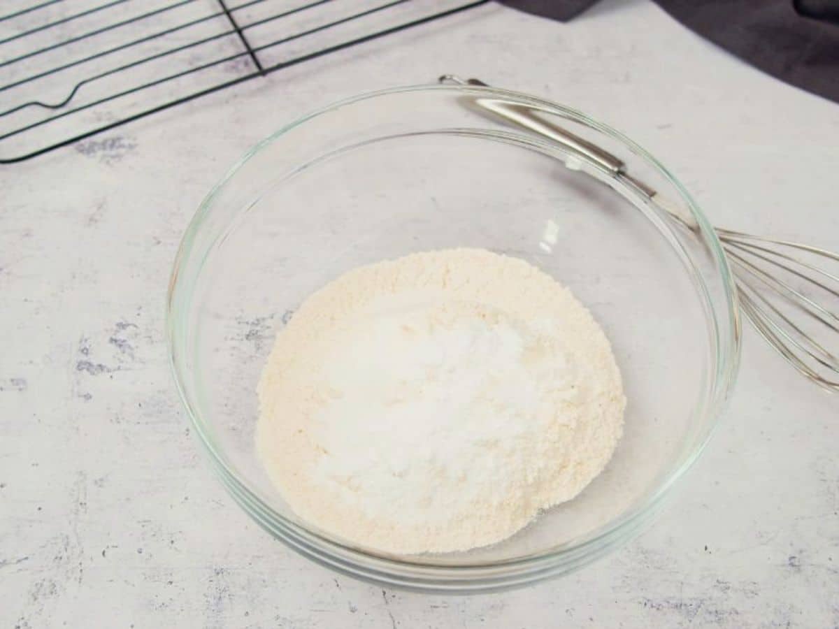 glass mixing bowl with dry ingredients on marble table by wire rack