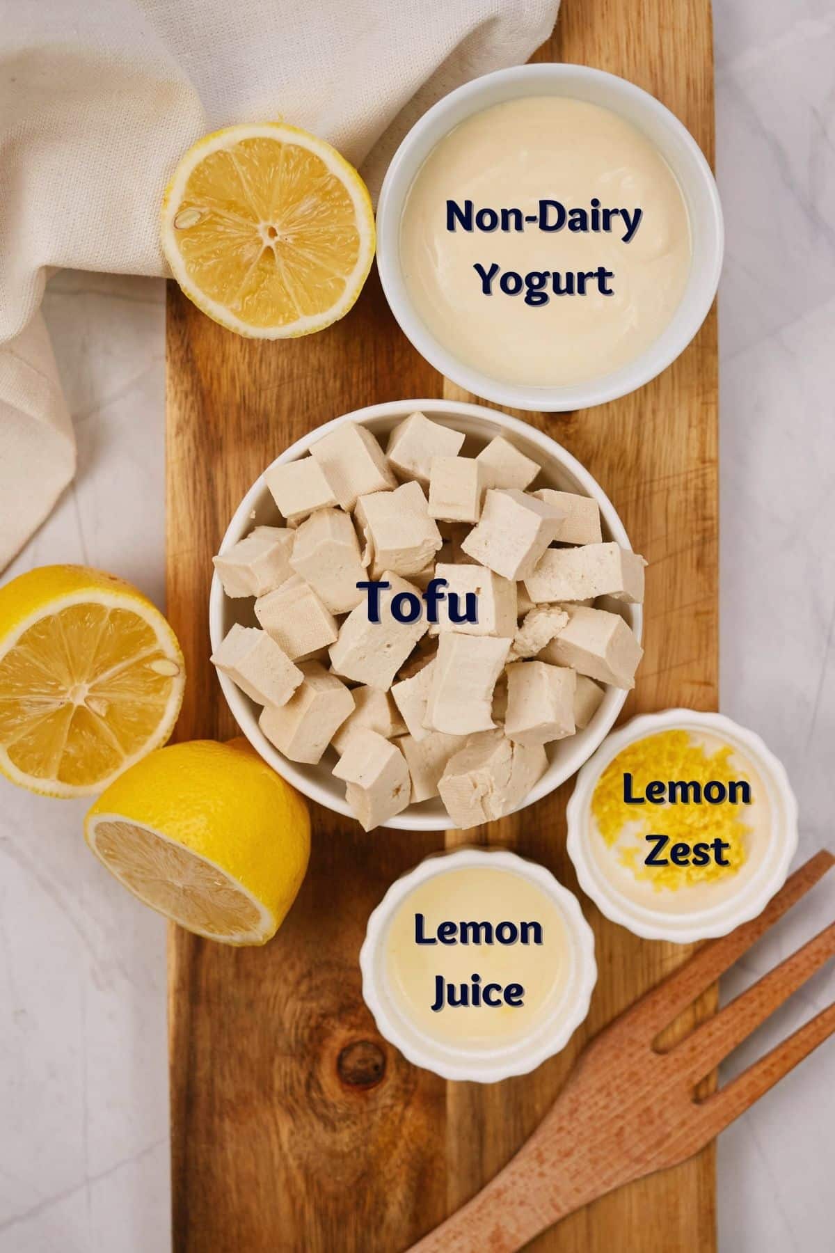 white ramekins of ingredients on wooden board sitting on marble table by lemon slices