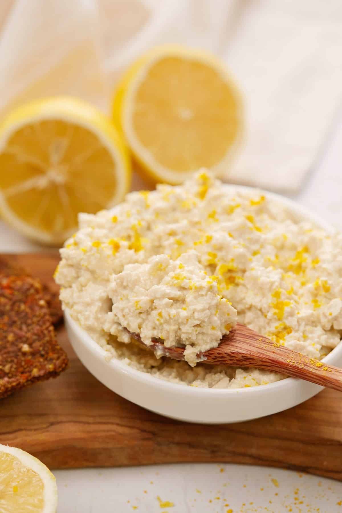 wooden spoon in side of bowl of vegan cottage cheese