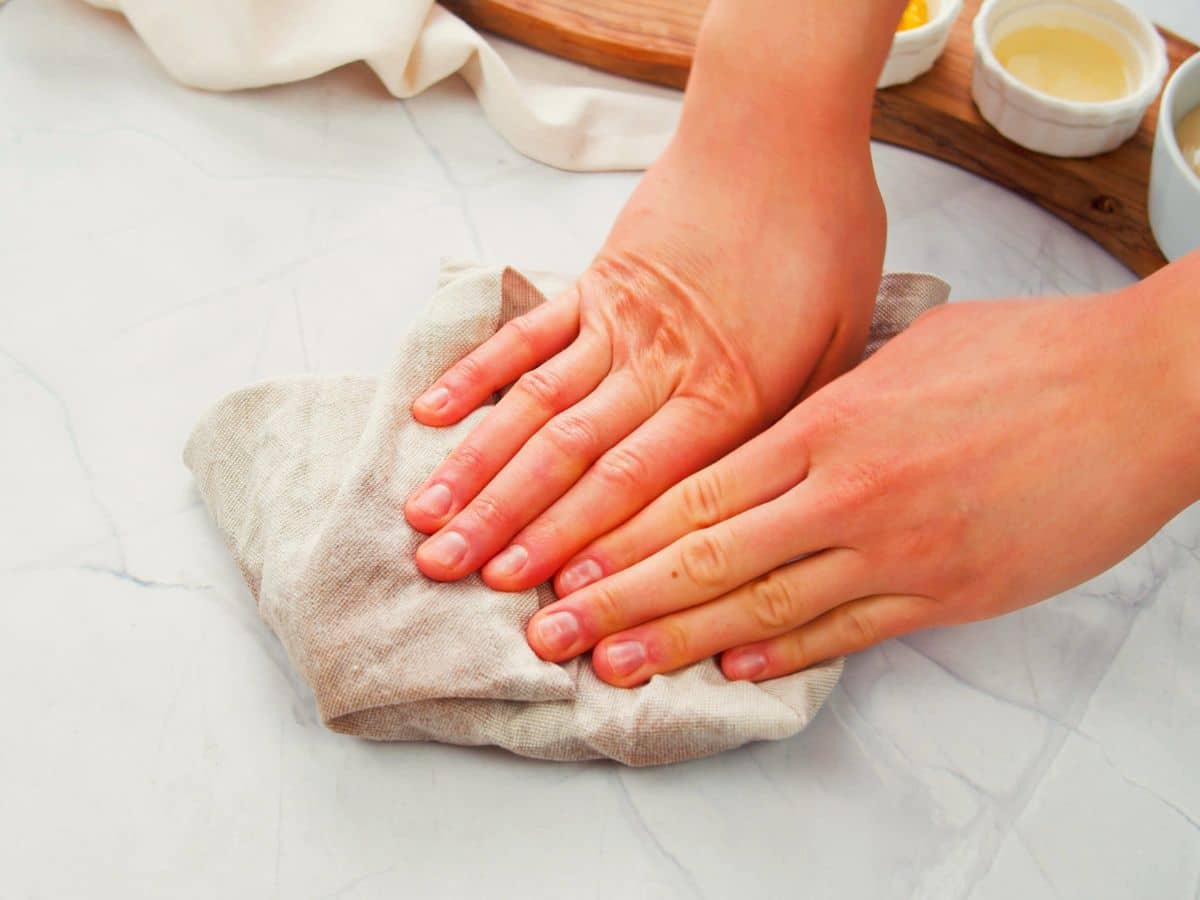 hands pressing tofu under tea towel