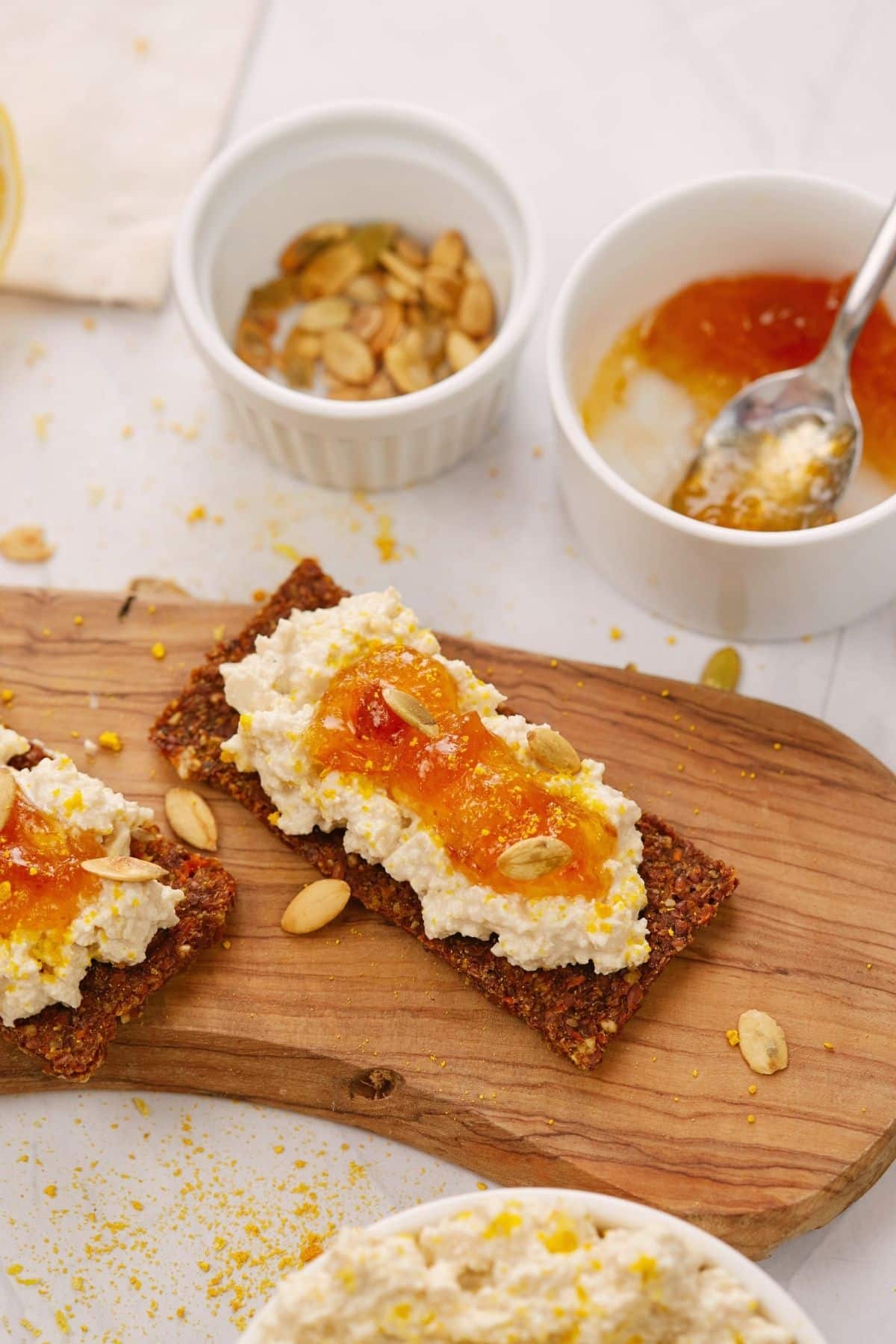 slices of toast topped by vegan cottage cheese and jam on wooden board