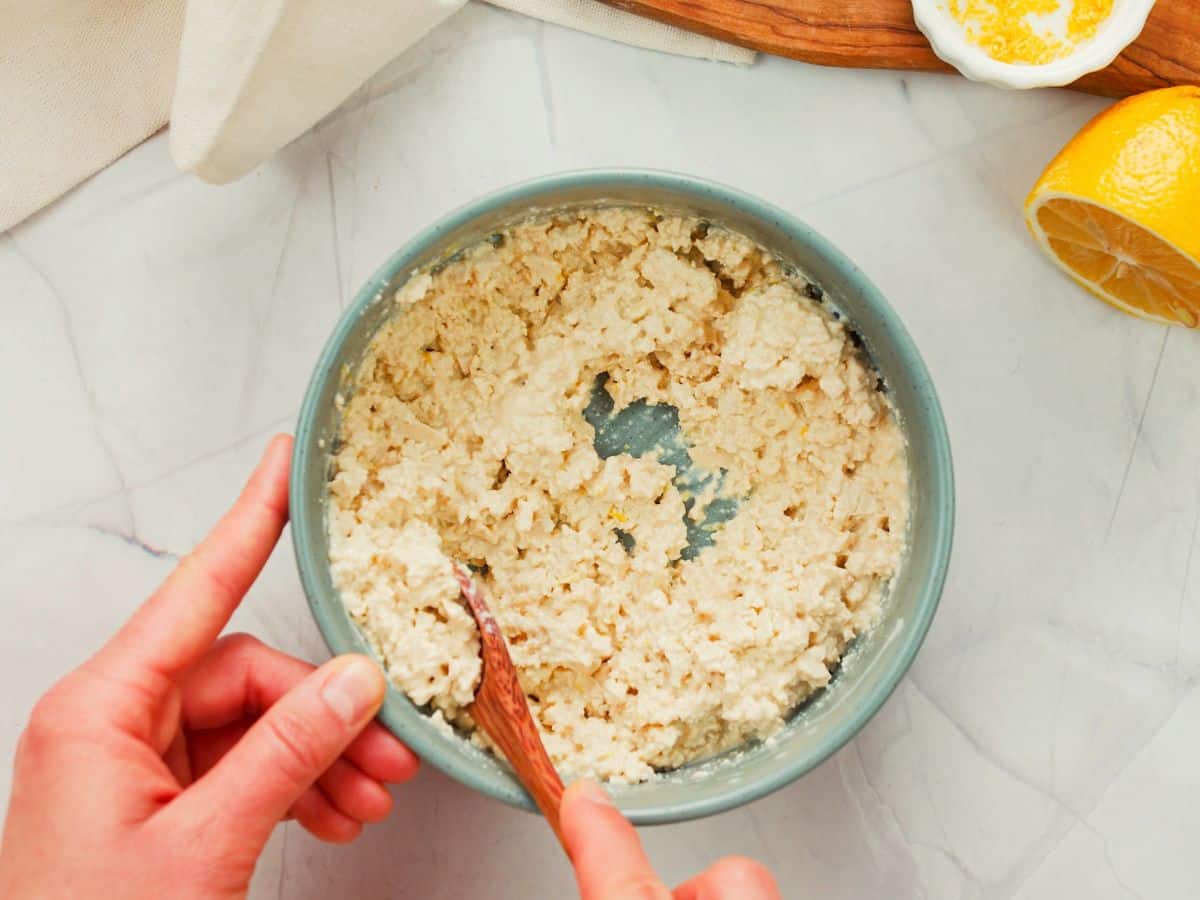 wooden spoon stirring cottage cheese in blue bowl