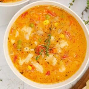 white bowl of vegetable soup on marble table