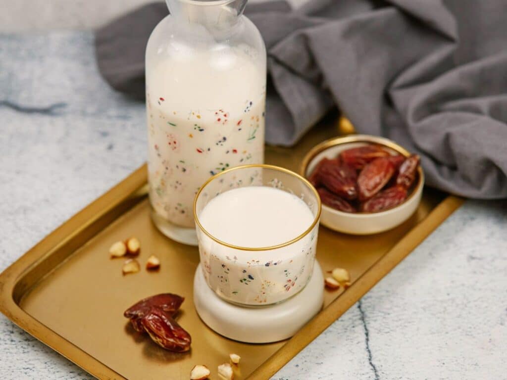 gray napkin on table by serving tray holding milk in small glass by glass jar