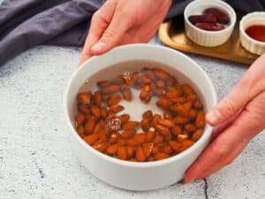 white bowl of almonds in water soaking