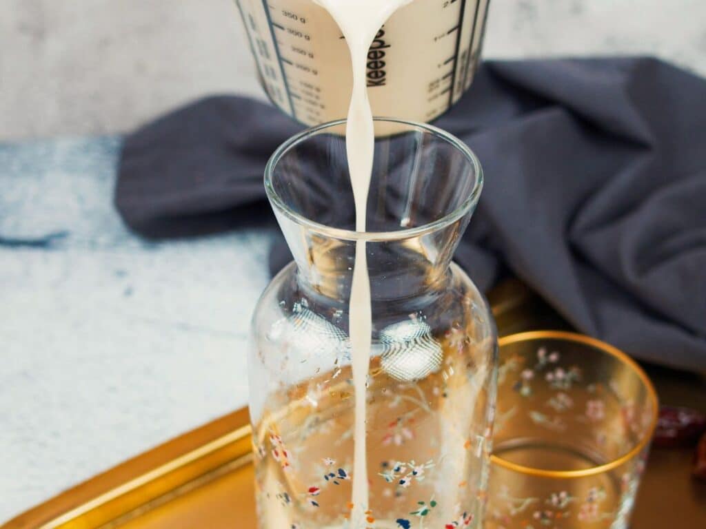 almond milk being poured into a glass jar