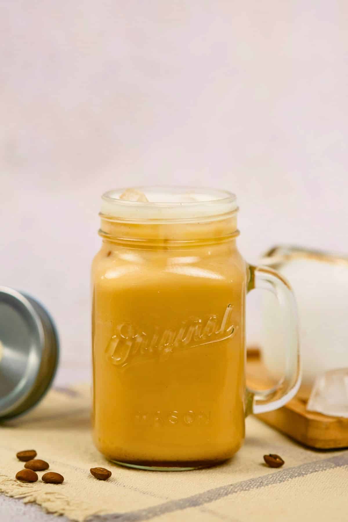 glass mason jar mug filled with brown sugar shaken espresso sitting on table