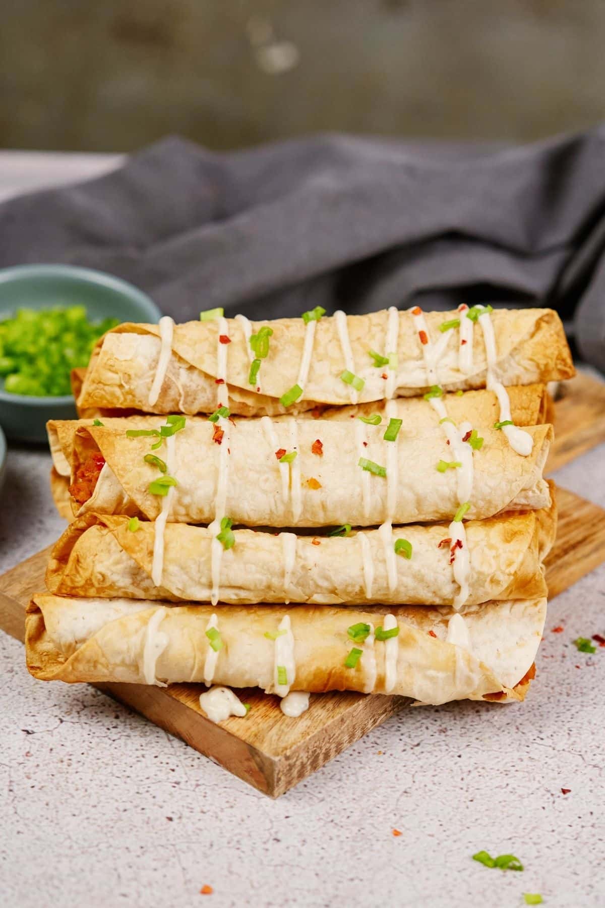 stacked vegan buffalo chickpea taquitos sitting on wood slab